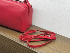 Red leather cylindrical shoulder bag detail, minimal 90s barrel bag strap view.