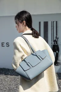 Detail view of light blue leather tote bag with structured flap and comfortable shoulder strap.