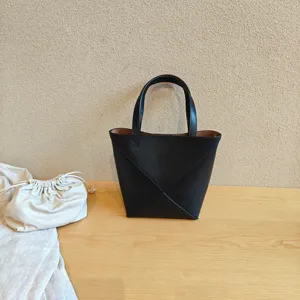Sac cabas pliable géométrique en cuir noir, détail avec poignées doubles et design élégant.