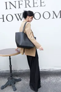 Black genuine leather tote bag detail view, minimalist large capacity commuting shoulder bag.