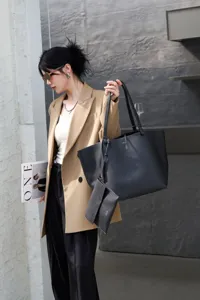 Black leather tote bag detail with small pouch, minimalist commuter handbag style.