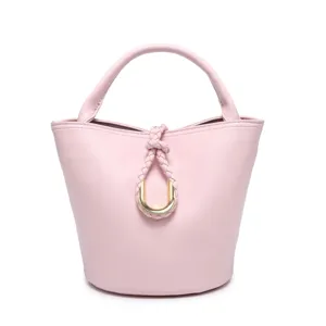 Detailed view of the elegant pink bucket bag, featuring a chic braided knot and golden ring.
