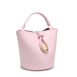 Chic pink leather bucket bag featuring a braided handle and elegant gold U-ring clasp.