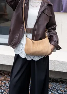 Detail shot of a minimalist brown suede underarm shoulder bag worn with casual outfit.