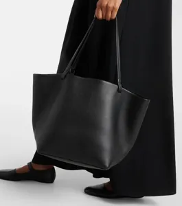 Detail view of a minimalist black leather tote bag, showcasing large capacity and texture.