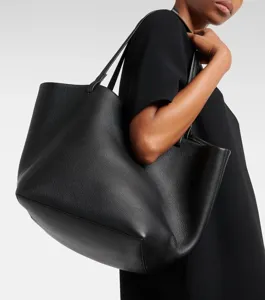 Detail shot of a sleek black leather tote bag featuring minimalist design, soft texture and thin straps.