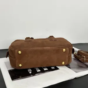 Braune Wildleder Bowlingtasche Detail, elegante Umhängetasche mit goldenen Füßen.