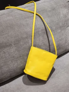 Sac seau minimaliste en cuir jaune pour femmes, sac bandoulière chic avec lanière fine.