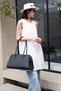 Detailed view of women black leather tote bag, soft pebble grain texture, long shoulder straps.