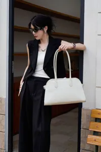 Detail view of white litchi grain cowhide shoulder tote bag with long handles in daily use.
