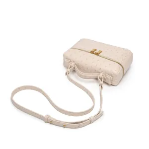 Vista detallada del bolso vanity cosmético beige claro con textura de avestruz y herrajes dorados.