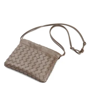 Brown woven leather crossbody bag with delicate strap and stylish knot detail closeup view.