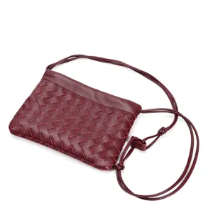 Detailed view of dark red woven leather crossbody bag with thin drawstring straps and knots.