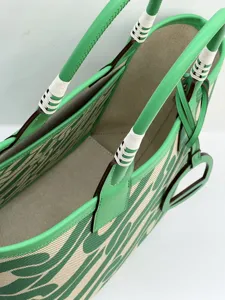 Detail view of the green and beige canvas tote bag with premium leather handles and stitch.