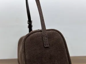 Detail shot of a dark brown suede 90s style baguette bag showcasing fine stitching and texture.