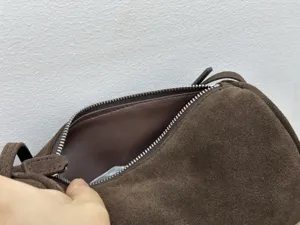 Brown suede shoulder bag zipper detail, premium leather texture, minimalist 90s style close up.