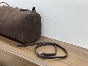 Brown suede cylindrical shoulder bag, stylish minimalist design with slim strap for women.