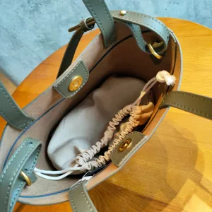 Détail intérieur de sac cabas seau en cuir vert olive avec compartiment et pochette.