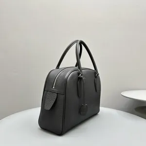 Detailed view of the black leather bowling handbag featuring top handles and secure zip closure.