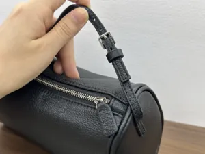 Leather cylinder bag detail, black cowhide barrel handbag zipper hardware showcase.