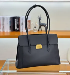 Detail view of black genuine leather tote bag featuring gold hardware and double straps.