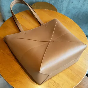 Vue détaillée du cabas en cuir marron montrant les panneaux pliés géométriques et les coutures.