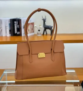 Brown leather tote bag detail, featuring durable top handles and a secure metal turn-lock closure.