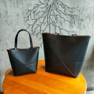 Vue détaillée de deux sacs cabas en cuir noir avec design de pliage géométrique sur table