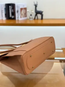 Brown leather handbag detail showing bottom metal feet, textured cowhide structured side.