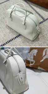 Detailed view of white genuine leather bowling handbag, featuring fine texture and metal zipper.