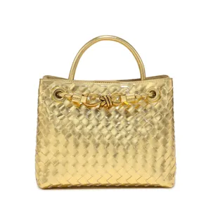 Gold woven leather handbag detail featuring stylish metal handle and knot hardware for women.