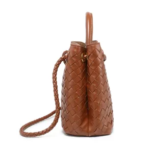 Brown woven leather bucket bag detail showing intricate craftsmanship and braided strap design.