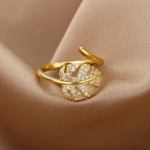 Macro view of 18K gold plated monstera leaf ring with sparkling zircons on silk background.