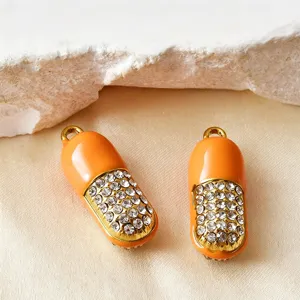 Nahaufnahme von orange-goldenen Kapsel-Anhängern mit funkelnden Strasssteinen für DIY-Schmuck
