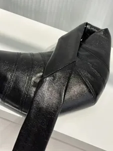 Close-up of black coated croissant bag detail, showing curved stitching and knotted strap.