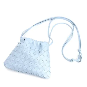 Close-up detail of light blue woven leather crossbody bag with drawstring and thin strap.