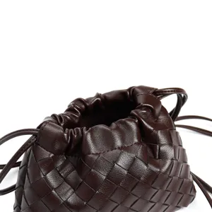 Close-up of dark brown woven leather drawstring bag showing premium intrecciato texture details.