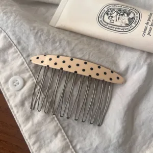 Detailed view of the chic polka dot acetate hair comb with metal tines, ideal for styling bangs.