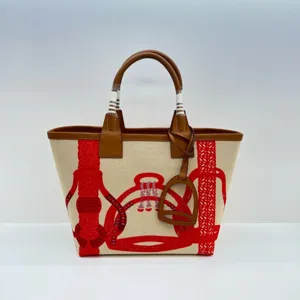Detail view of the canvas tote bag featuring equestrian motifs and leather top handles.