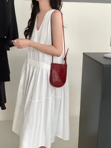 Primo piano dettagliato sulla piccola borsa a tracolla in pelle rossa minimalista.