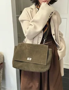 Olive green suede shoulder bag detail, flap design with metal turn-lock closure and strap.