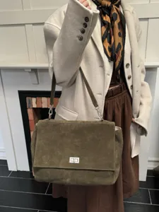Detailed view of women's olive green suede shoulder bag with elegant turn lock and strap.