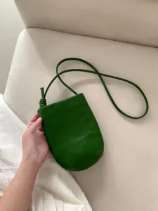 Primo piano della borsa per telefono in pelle verde scuro con texture morbida e cinturino annodato.
