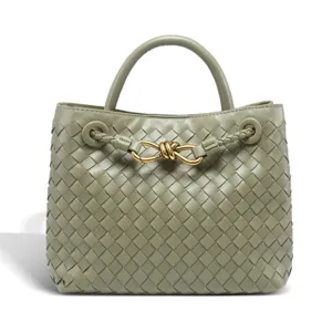 Close-up detail of the woven leather texture and gold knot hardware on the elegant green handbag.
