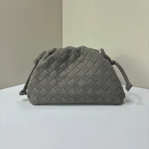 Grey woven suede clutch bag detail showcasing intricate leather intrecciato craftsmanship.