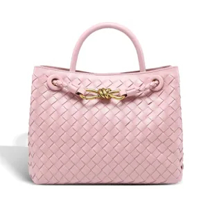 Detailed close-up view of the pink woven leather handbag featuring elegant gold knot hardware.