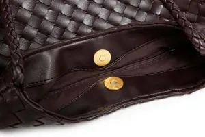 Handwoven leather shoulder bag detail showing interior lining and metal magnetic snap closure.