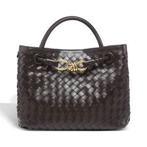 Close-up view of the dark brown woven leather handbag featuring luxury gold-tone knot hardware.