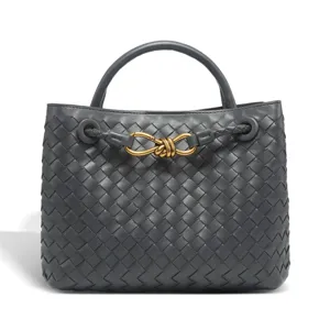 Detailed view of the dark grey woven leather handbag featuring elegant metal knot closure.