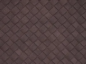 Close-up detail shot of dark brown woven leather material showing exquisite texture and craft.